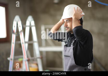 Construction worker putting helmet working in a house under reform Stock Photo