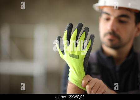 Construction worker putting protective glove before work in a house under reform Stock Photo