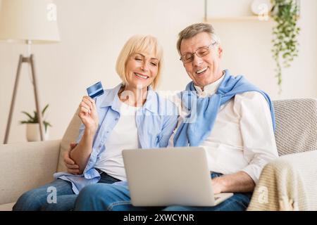 Excited older couple doing online shopping on laptop Stock Photo
