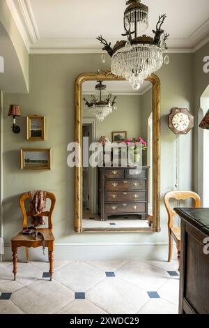 Gilt framed mirror in 'Ball green' hall with limestone tiles in Wimbledon home, south-west London, England, UK. Stock Photo