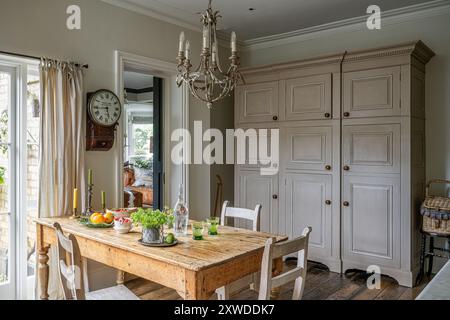 Farmhouse kitchen with wall clock and large storage cupboards in Wimbledon home, south-west London, England, UK. Stock Photo