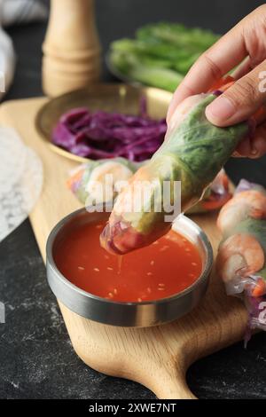 Female Hand Dipping Vietnam Fresh Vegetable Spring ROll to the Sweet and Sour Sauce with Sesame Seed Stock Photo