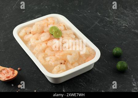 Frozen Peeled Shrimp on White Plate, Above Black Marble Table Stock Photo