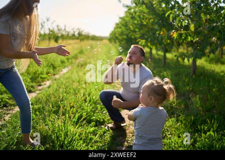 family of four is playing catch bubbles in the garden Stock Photo