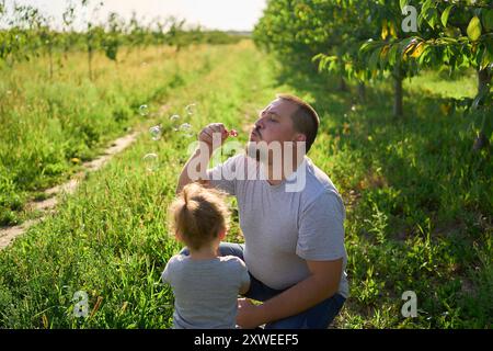 family of four is playing catch bubbles in the garden Stock Photo
