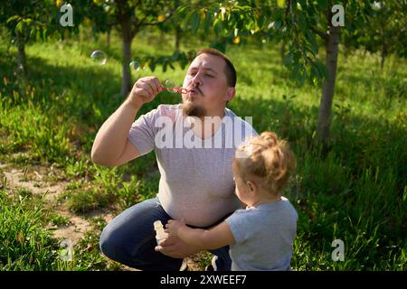family of four is playing catch bubbles in the garden Stock Photo