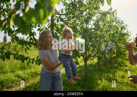 family of four is playing catch bubbles in the garden Stock Photo