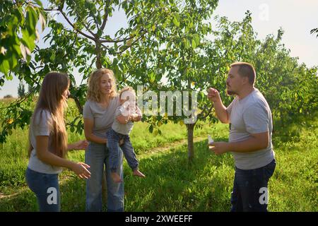 family of four is playing catch bubbles in the garden Stock Photo
