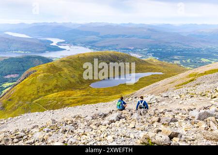 Hikers resting on the way up to Ben Nevis summit, view overlooking Halfway Lochan (Lochan Meall an t-Suidhe), Highlands, Scotland UK Stock Photo