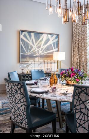 Geometric artwork with similar pattern on dining chairs in luxury modern British home. London, UK Stock Photo