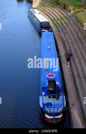 Couple mooring narrowboat to riverside on the River Severn at Upton Upon Severn, Worcestershire, UK Stock Photo