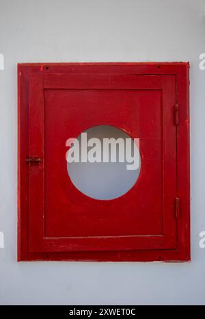 White wall of a house with a bright red case with a circle hole, prepared for a fire extinguisher. Empty in this case. Djerba, Tunisia, Africa. Stock Photo
