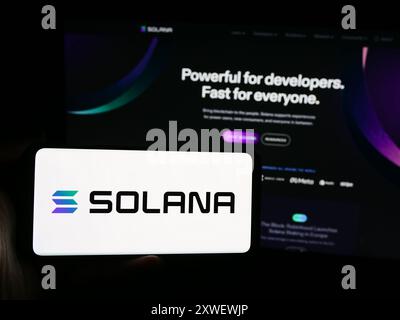 Person holding smartphone with logo of blockchain platform company Solana in front of website. Focus on phone display. Stock Photo