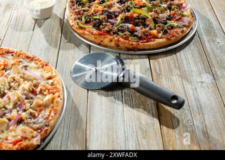 A view of a pizza slicer tool among several pizza pies. Stock Photo