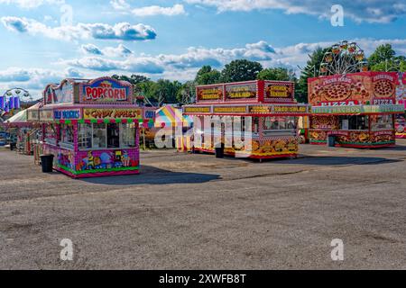 Variety of food trailers at a carnival at the fair all set up ready to go bright and colorful attractions with the rides in the background on a sunny Stock Photo