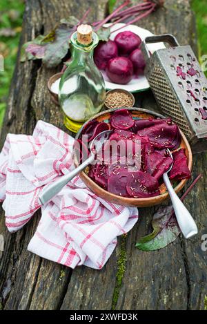 Bowl of Fresh Beetroot salad with oil and cumin seeds on wooden table in the garden Stock Photo