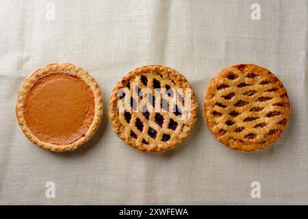 Overhead still life of fresh baked holiday pies on a burlap table cloth. Stock Photo