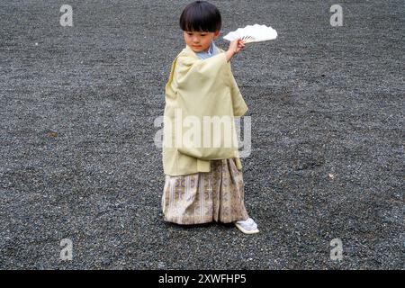 A Kimono dressed young boy poses for images with his fan at Meji Shrine in Tokyo, Japan. Stock Photo