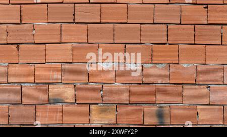 Red brick wall texture of an unfinished house under construction, showing a rough, tiled surface. Stock Photo