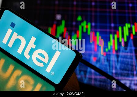 In this photo illustration, the Intel logo is displayed on a smartphone screen against a computer screen what displays stock graphs on August 19, 2024 as stock markets stabilise after a setback at the beginning of August. Stock Photo