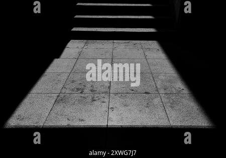 Sunlit Staircase and Concrete Tiles: Wide-Angle Perspective of Light and Shadow in an Alley Street. Black and white. Stock Photo