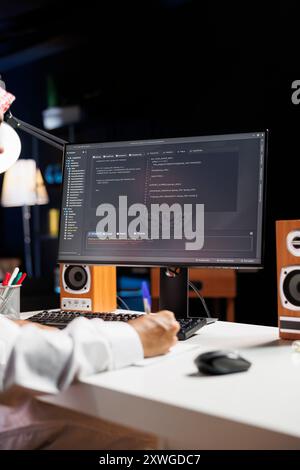 Detailed shot of computer screen displaying sleek software app interface, highlighting app development and user interface design. Image shows man engrossed in writing and examining code. Stock Photo