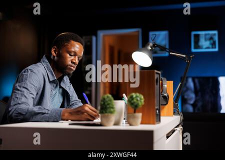 Male developer taking notes at online finances webinar, writing down information to learn accounting work. Young man listening to e learning program trainee, management support. Stock Photo