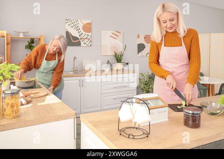 Mature female friends cooking in kitchen Stock Photo