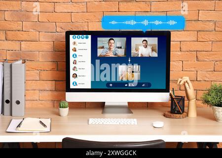 Interface of software used by people for video chatting on screen of computer monitor on table Stock Photo