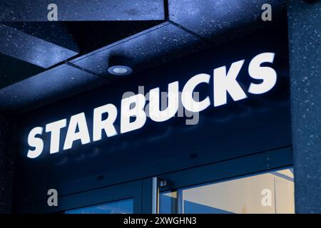 Poznan, Poland. 13 August, 2024: Illuminated Starbucks Storefront Sign at Night Stock Photo