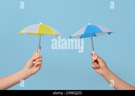 Female hands with different mini umbrellas on blue background Stock Photo