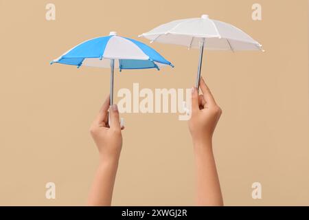 Female hands with different mini umbrellas on beige background Stock Photo