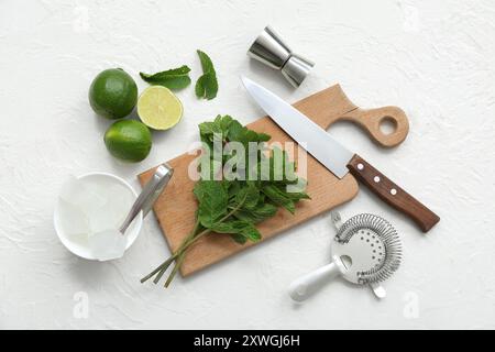 Wooden cutting board, knife and ingredients for preparing mojito on white background Stock Photo