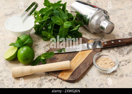 Wooden cutting board, pestle, knife and ingredients for preparing mojito on grunge background, closeup Stock Photo
