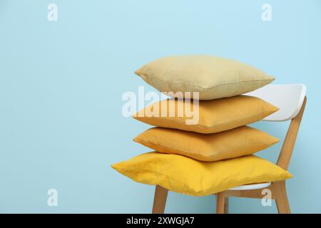 Stack of cushions on chair near blue wall in room Stock Photo