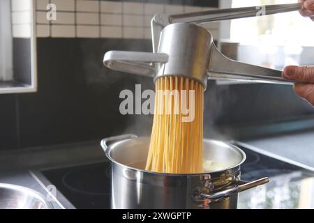 Spaetzle dough is pressed through a spaetzle press Stock Photo