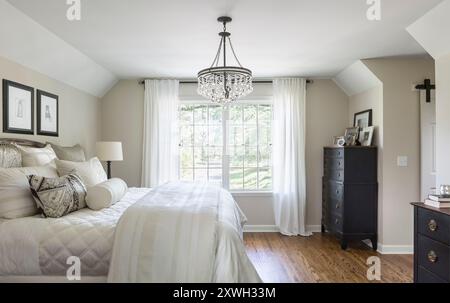 Soft neutral tones in master bedroom with slight pitched ceiling and beautiful bedding Stock Photo