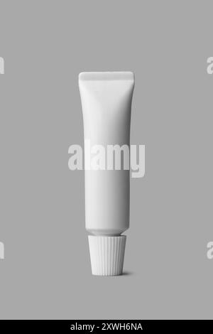 tube with white cap in close-up, mock-up template for toothpaste, glue, cream, gel or shampoo, blank package isolated on gray background, medicine Stock Photo