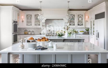 High end white kitchen with two islands and lots of beautiful flowers and dishes Stock Photo