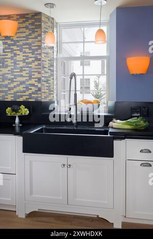 Kitchen sink and window with beautiful black anthracite countertops, honed black granite sink and irridescent tile backsplash Stock Photo