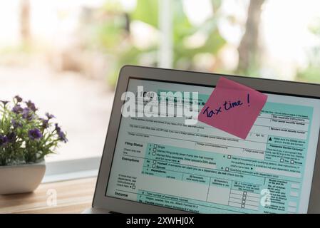 tax return concept. tax time post-it on alarm clock and Individual income tax return form online. Stock Photo