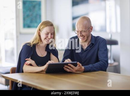 Symbolfoto. Eine Frau und ein Mann sitzen zusammen an einem Tisch mit einem Tablet und unterhalten sich. Berlin, 13.08.2024. Berlin Deutschland *** Sy Stock Photo