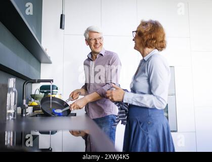Symbolfoto. Ein aelteres Paar steht in der Kueche und waescht zusammen ab. Berlin, 13.08.2024. Berlin Deutschland *** Symbolic photo An elderly couple Stock Photo