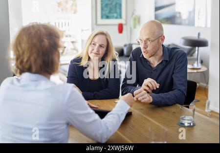 Symbolfoto zum Thema Beratung. Eine junge Frau und ein junger Mann sitzen zu Hause zusammen an einem Tisch und werden beraten. Berlin, 13.08.2024. Ber Stock Photo