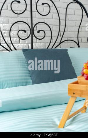 Wooden Breakfast Tray With Teapot, Grapes, and Cup on a Blue Bed Stock Photo