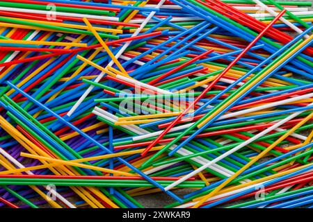 many multi-colored plastic tubes for cocktail on Colored background, top view. Stock Photo