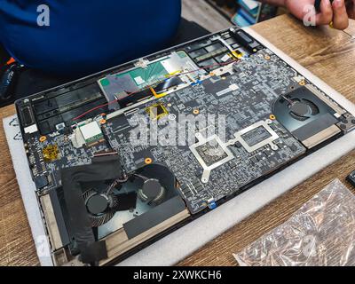 Computer technician disassembling mainboard with circuit of laptop repairing and upgrade technology in repair shop Stock Photo