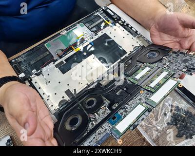 Computer technician disassembling mainboard with circuit of laptop repairing and upgrade technology in repair shop Stock Photo