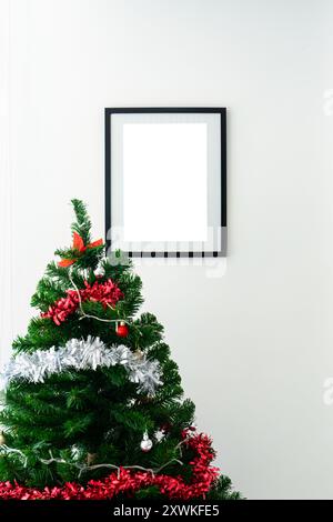 Empty black picture frame with christmas tree with ball on white wall background Stock Photo