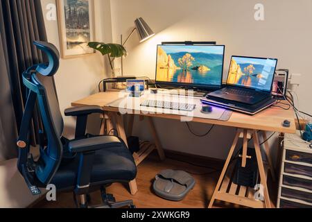 Interior workplace of photographer with laptop, monitor, computer device, lighting lamp, green leaf on wooden table and ergonomic chair in the house Stock Photo